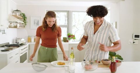 Diverse Couple Joyfully Preparing Breakfast Together in Modern Kitchen