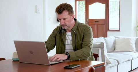 Middle-Aged Man Working Remotely at Home on Laptop