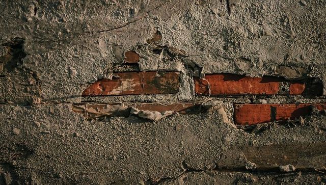 Peeling Plaster Revealing Red Brick and Lath on Weathered Rustic Wall with Cracked Texture