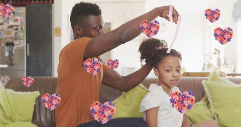 Father styling daughter's hair with floral hearts