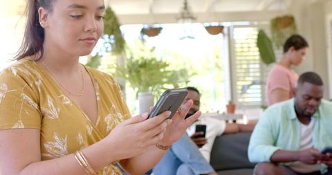 Diverse Friends Relaxing with Smartphones in Modern Living Room