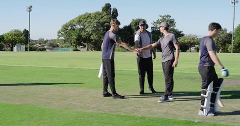 Cricket team huddling and performing hand-stack on suburban pitch during daytime practice