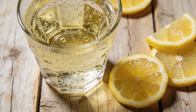 Sparkling lemon beverage closeup in faceted glass on rustic wooden planks