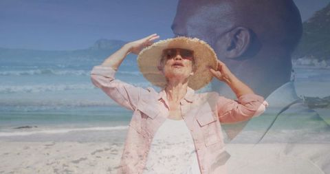 Senior woman adjusting straw hat on sunny beach with translucent businessman overlay