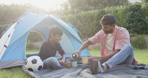 Father and Son Bonding Outdoors with Soccer Ball and Tent