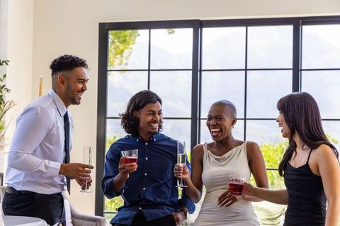 Semiformal african american and multiracial friends toasting with champagne in modern lounge