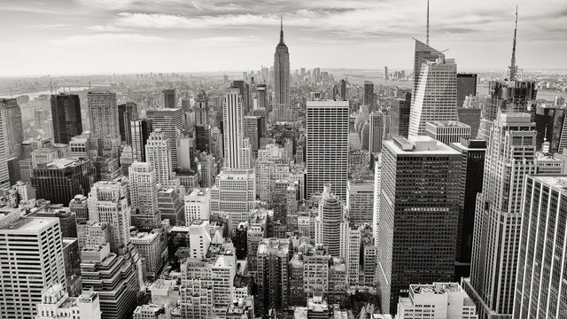 This striking image captures an aerial view of the dense skyscraper buildings of New York City in black and white, making it perfect for use in projects related to urbanization, architecture, or metropolitan life. Ideal for city guides, travel publications, and financial district presentations.