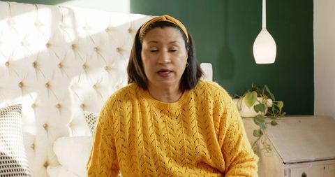 Mature woman speaking while sitting on elegant tufted bed
