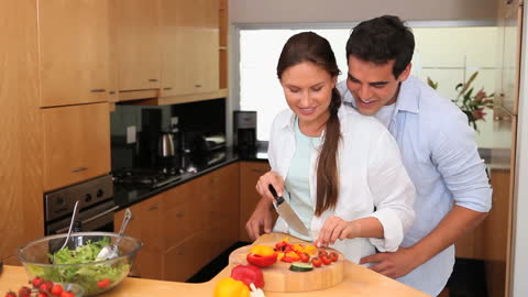 Couple Embracing in Kitchen While Preparing Salad Together