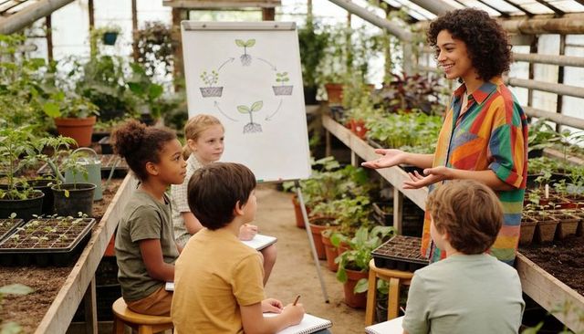 Greenhouse classroom teaching kids plant life cycle seedlings notebooks smiling teacher