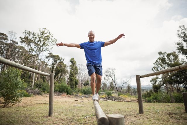 Fit man balancing on hurdles during obstacle course training at boot camp