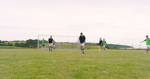 Diverse Soccer Players Training on Green Field with Goal Frame