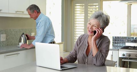Senior Woman Talking on Phone with Laptop in Kitchen - Download Free Stock Images Pikwizard.com