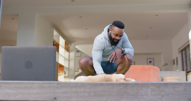 Fit man bonding with dog while having home workout session in stylish modern living room. Ideal for topics related to fitness, pet ownership, home gym, lifestyle, and indoor activities.