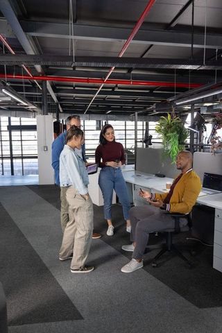 Gathering and brainstorming among diverse coworkers in modern open-plan office