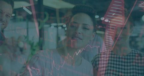 Mature woman analyzing financial charts through glass with red upward arrow, team collaboration