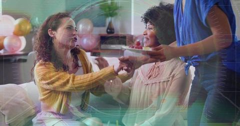 Friends passing dessert plate and laughing during cozy birthday celebration at home