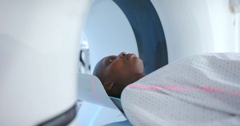 African american woman undergoing mri head scan with pink laser alignment