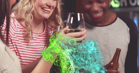 Friends toasting wine and beer at neon-lit bar with colorful splash effect