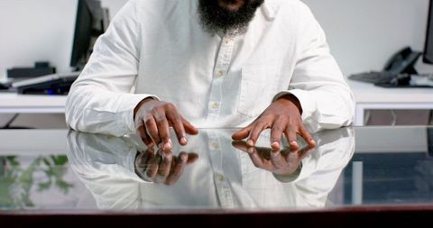 Business professional tapping fingers on glass desk in modern office