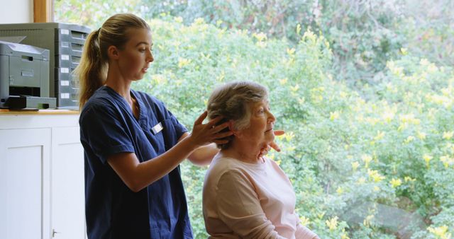 Caregiver Massaging Elderly Woman's Neck near Window - Download Free Stock Images Pikwizard.com