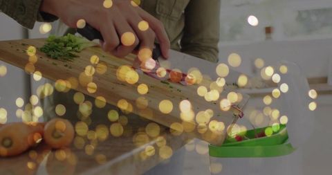 Woman chopping carrots on wooden cutting board over compost bin with warm bokeh lights