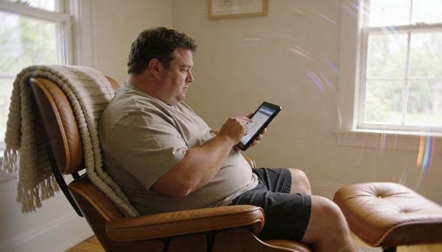 Man using tablet while sitting in leather recliner near window daylight