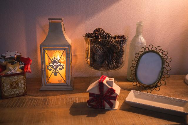 Rustic Christmas decoration setup with lantern, pinecones, and holiday ornaments on wooden table. Ideal for seasonal greetings, home decor inspiration, holiday advertisements, Christmas blogs, and festive social media posts.
