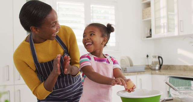 Happy african american mother and daughter cooking and giving high five in kitchen. staying at home in self isolation during quarantine lockdown.