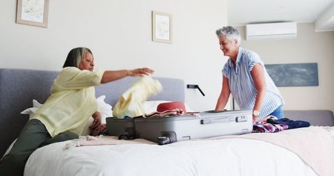 Senior Couple Packing Suitcase for Vacation Together in Bedroom