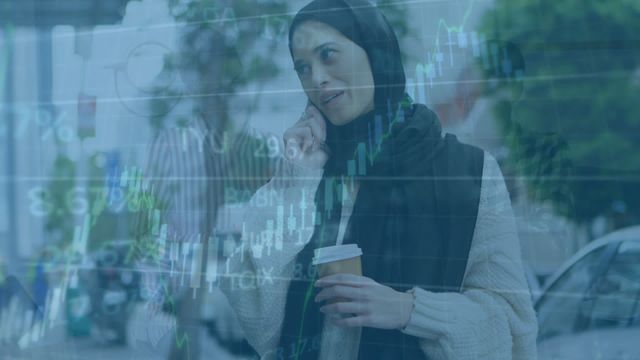 Stock photo featuring a multicultural team interacting amidst various financial data overlays. A woman in a hijab talks on the phone, symbolizing modern business communication and cultural diversity. Useful for illustrating themes of global business, financial technology, team collaboration, and the integration of traditional and modern workplace dynamics.