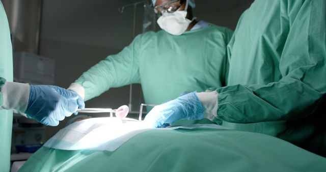Surgeons in sterile green gowns conducting a complex operation in a modern operating room under bright surgical lights. This image conveys concepts such as healthcare, medical procedures, lifesaving interventions, precision surgery, and the dedication of healthcare professionals. Ideal for use in medical publications, healthcare websites, and educational materials.