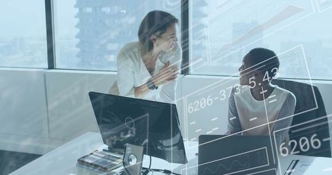 Collaborating Businesswomen Analyzing Data on Monitors in Modern Office