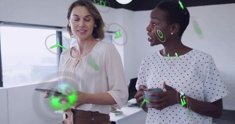 Two colleagues collaborating with tablet and mug using ar interface in modern office