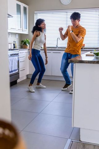 Young couple dancing in bright modern kitchen enjoying playful morning together