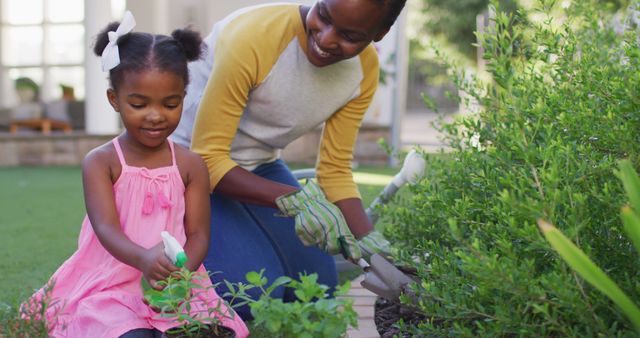 Mother and daughter spend time in garden planting herbs. They are both smiling and enjoying the outdoor activity. Perfect for promoting family bonding, outdoor activities, gardening products, and educational content about nature and plants.