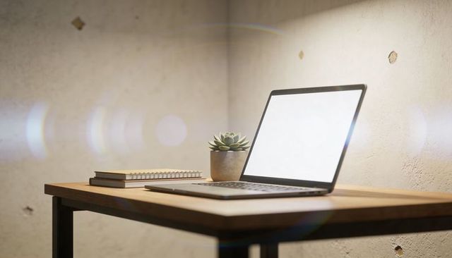 Minimal laptop workspace with blank screen, succulent plant and spiral notebook on desk