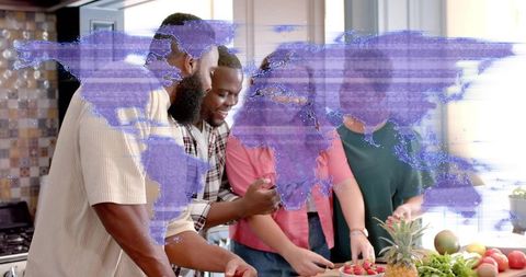 Smiling diverse friends preparing fresh fruit in kitchen with digital world map overlay