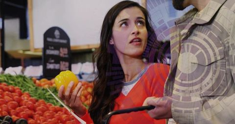 Couple comparing yellow bell pepper at farmers market choosing fresh produce