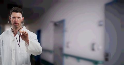Caucasian Male Doctor Holding Stethoscope in Hospital Corridor