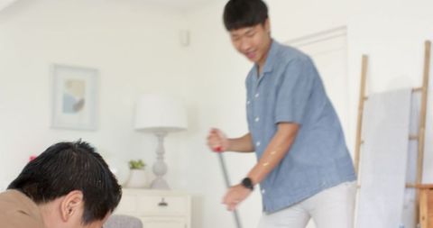 Man sweeping living room floor for housekeeping chores