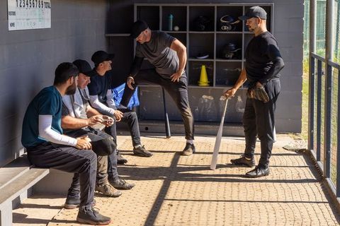 Baseball teammates gathering in sunlit dugout preparing for game camaraderie and strategy