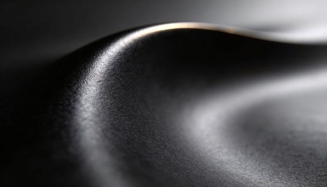 Curved matte metal surface revealing dramatic ridge and rim highlight, abstract macro
