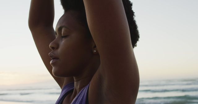 African american woman practicing yoga and meditating on sunny beach. healthy and active time beach holiday.