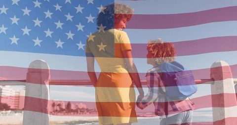Mother and son holding hands on boardwalk with us flag overlay showing patriotic bond