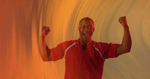 Energetic man flexing double biceps wearing red athletic shirt against warm orange gradient