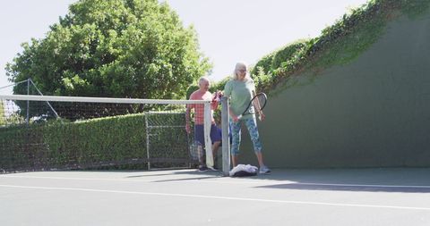 Senior Couple Arriving at Tennis Court on Sunny Day