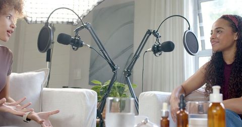 African american women recording cozy home podcast on sofas with pro boom microphones