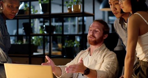 Diverse Team Collaborating on Project at Night in Modern Office