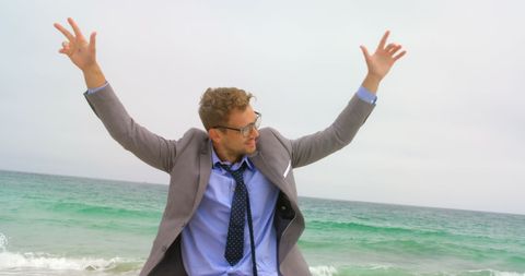 Joyful businessman dancing on beach in suit